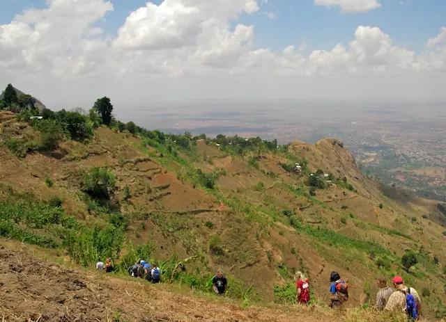 Walkers on a green hillside above the Rift Valley