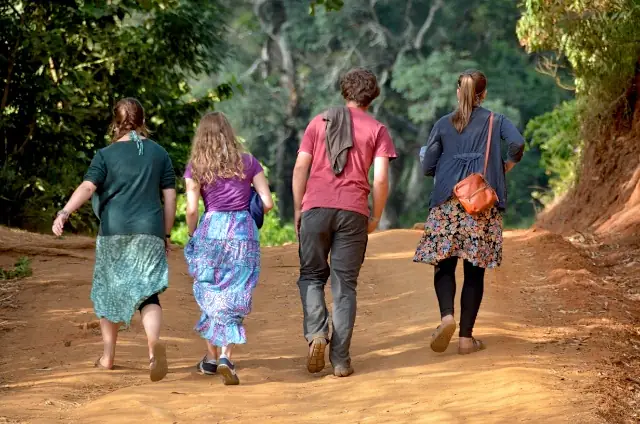 Guests walking along a red-earth path near Karatu