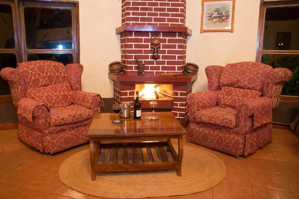Bar lounge with red armchairs around a brick fireplace