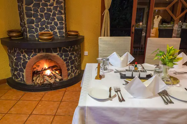 Dining tables set beside a curved stone fireplace