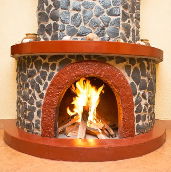 Round stone fireplace with a fire burning