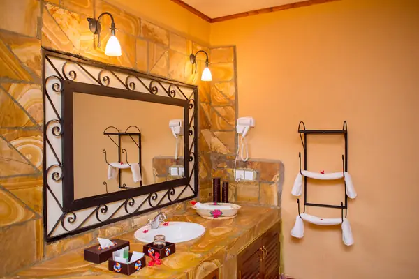 En-suite bathroom with stone vanity and wrought-iron mirror