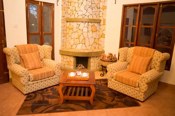 Upholstered armchairs in front of the suite’s stone fireplace