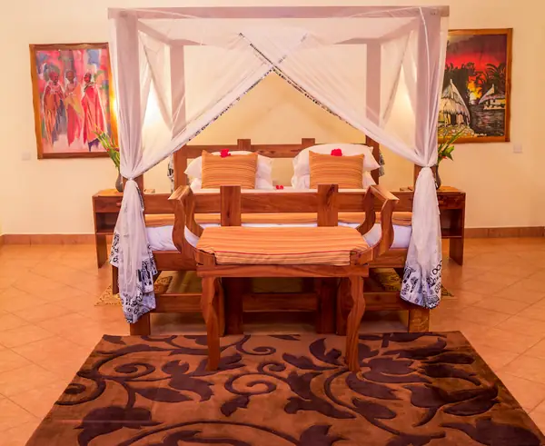 Carved wooden bench and table at the foot of a canopy bed