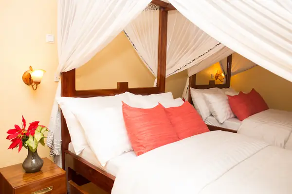 Tembo Family House bedroom with coral cushions under a canopy